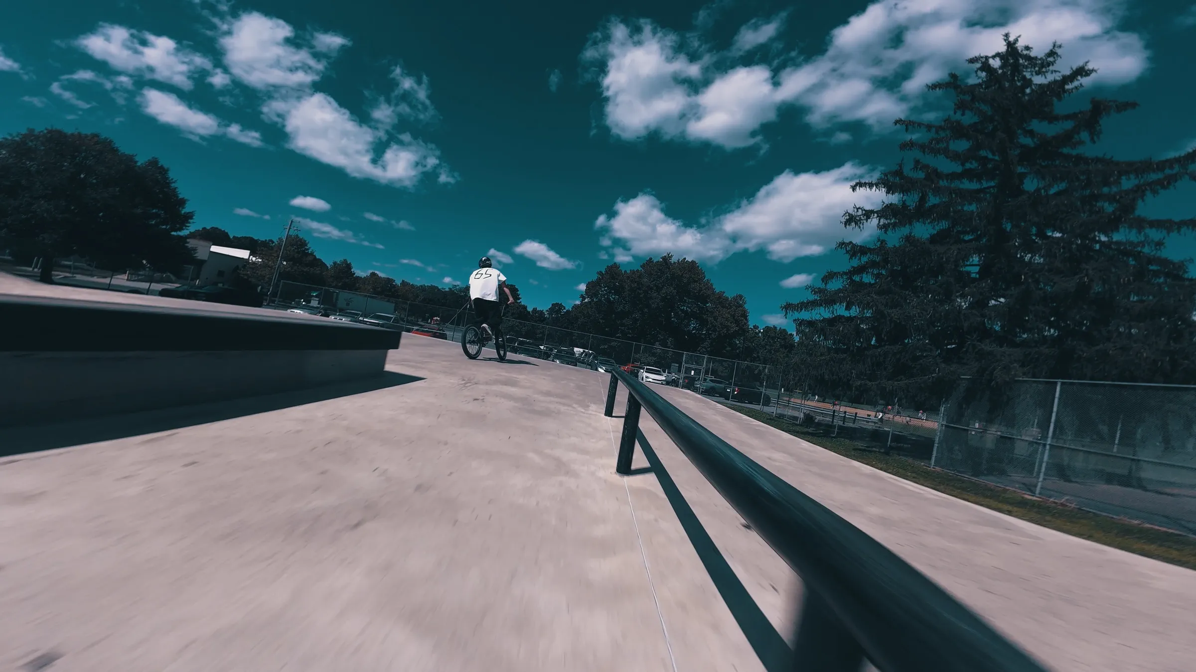 Low FPV perspective following a BMX rider through a skatepark