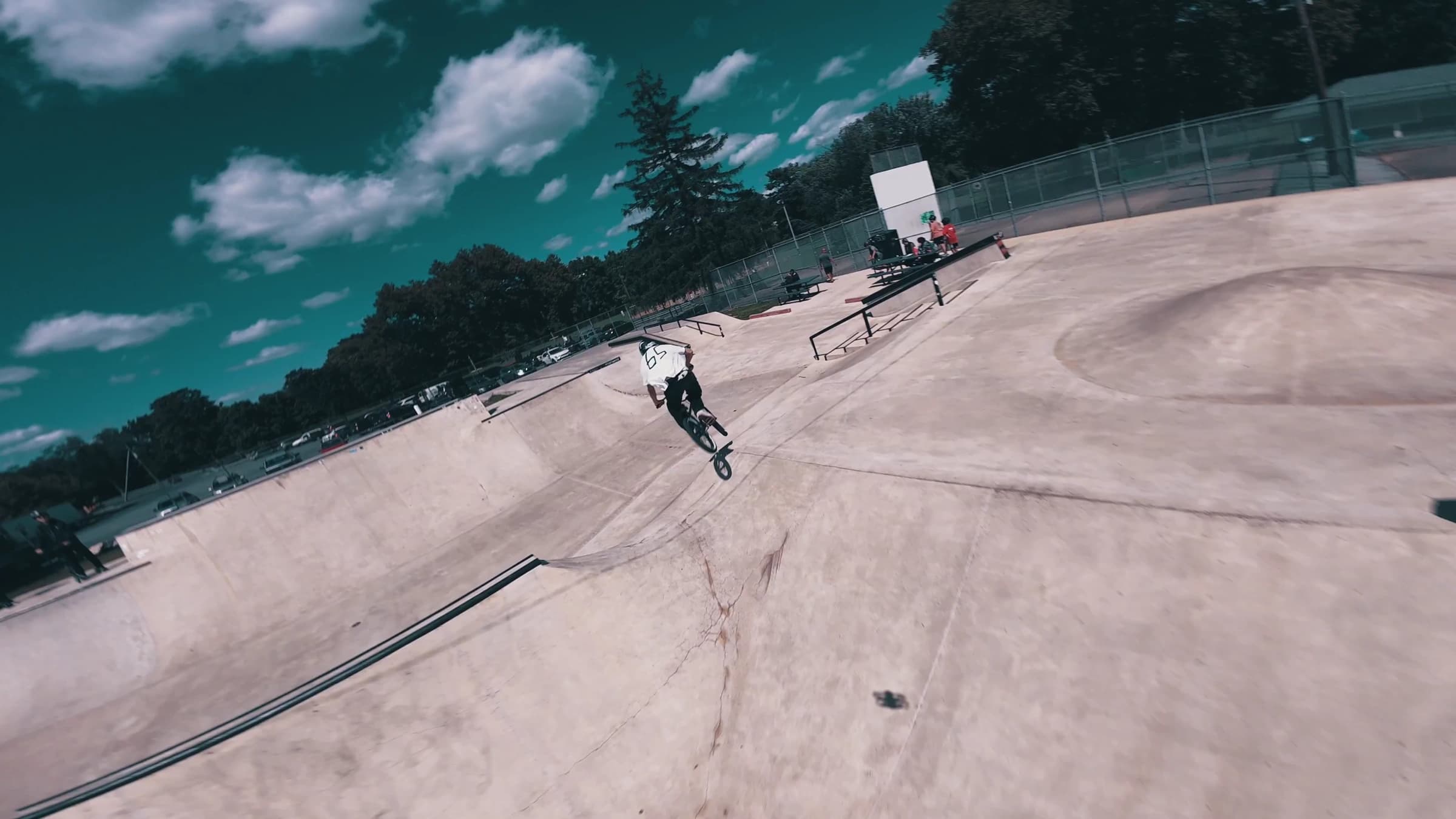 FPV drone chasing a BMX rider across skatepark concrete