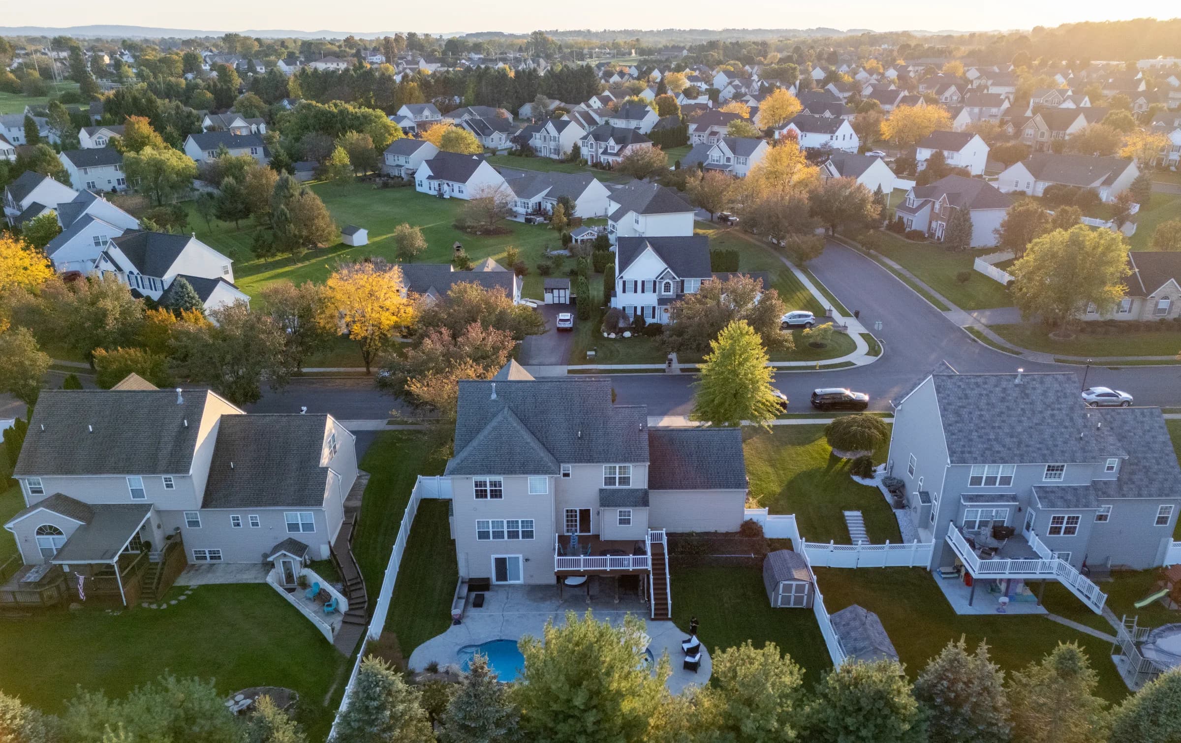 Golden-hour aerial showing a finished home, pool, and neighborhood